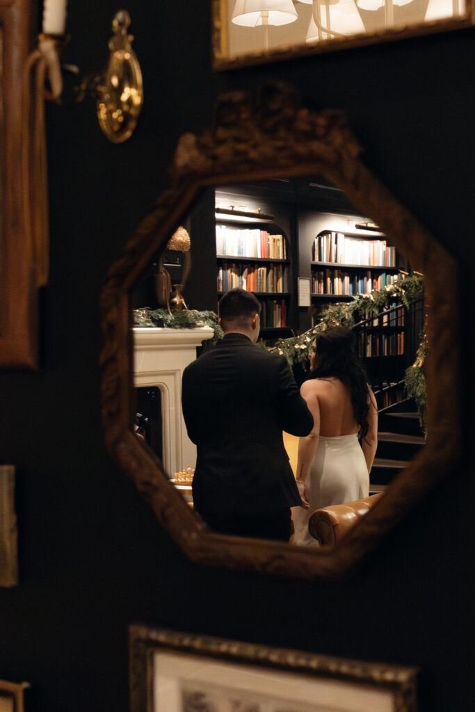 Bride and groom standing together in the library at Hotel 1928, intimate and moody.