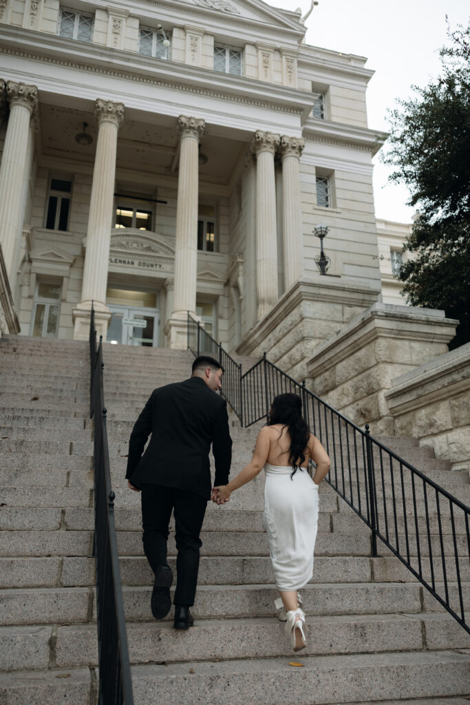 Bride and groom walking up the steps of the historic Waco courthouse during their elopement.