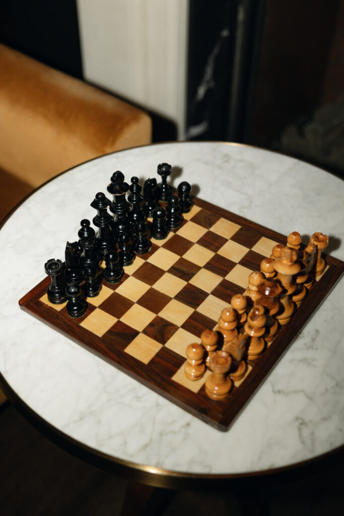 Couple laughing while playing chess in the library during their elopement.