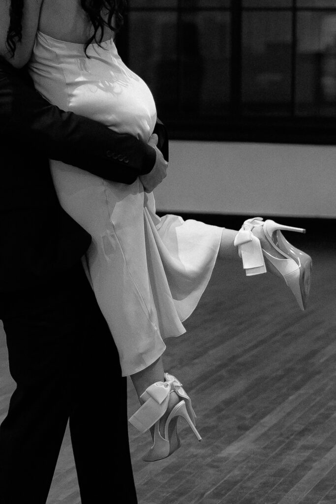 Close embrace of the couple dancing in Hotel 1928 ballroom, documentary style.