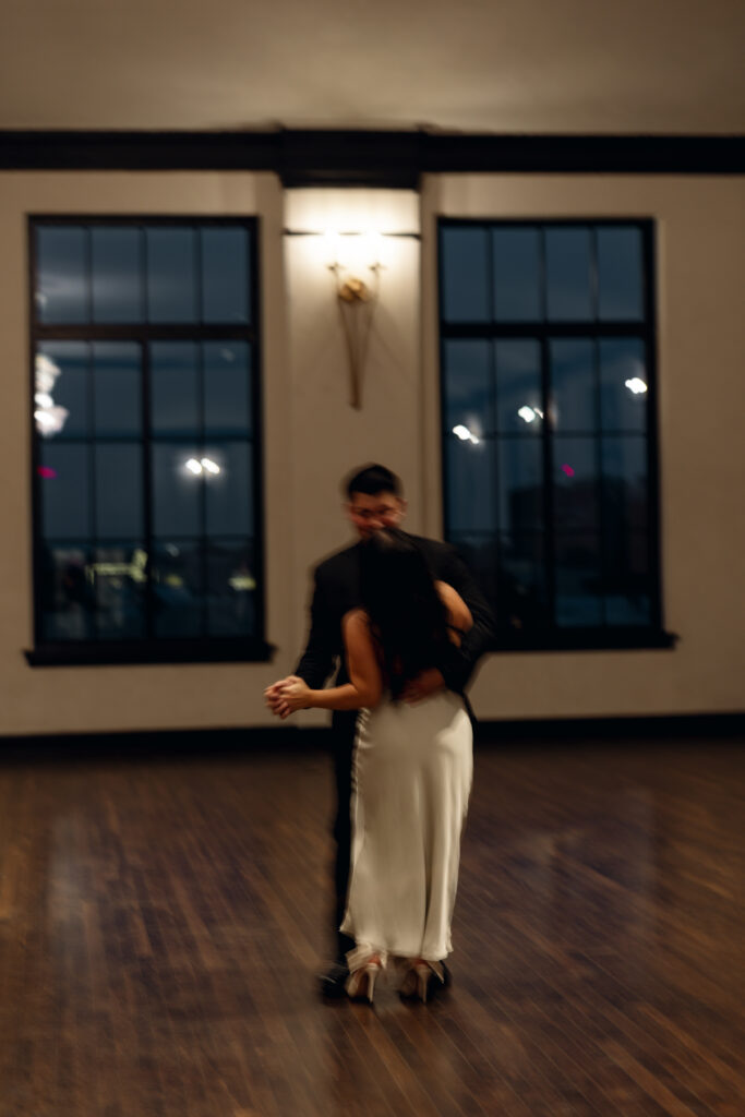 Bride and groom dancing in the ballroom at Hotel 1928, captured naturally.